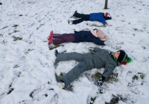 dzieci robią na śniegu aniołki